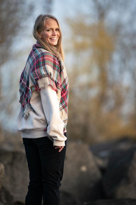 An woman rejuvenating herself standing on the rocks by a forest allowing functional breathwork to support her nervous system.