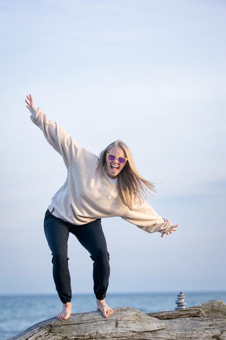 A woman smiling widely loving her retrained breathing pattern with a new sense of energy, arms wide open welcoming the adventures of life feeling peaceful.