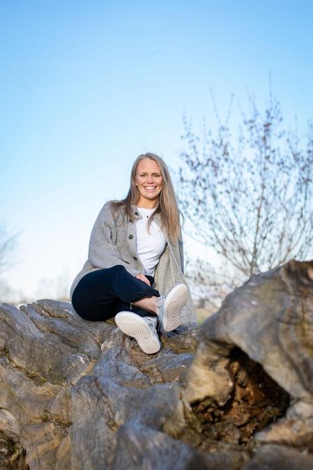A portrait of Randi, the breathwork facilitator smiling rested in nature with blue skies loving the ability to educate humans on their breathwork and nervous system supports to help the population.