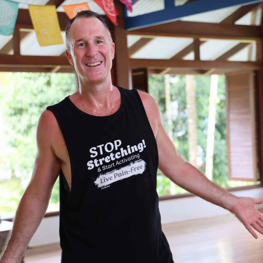 Yogi Aaron wearing a black shirt that says Stop Stretching, Start Activating, Live Pain-Free