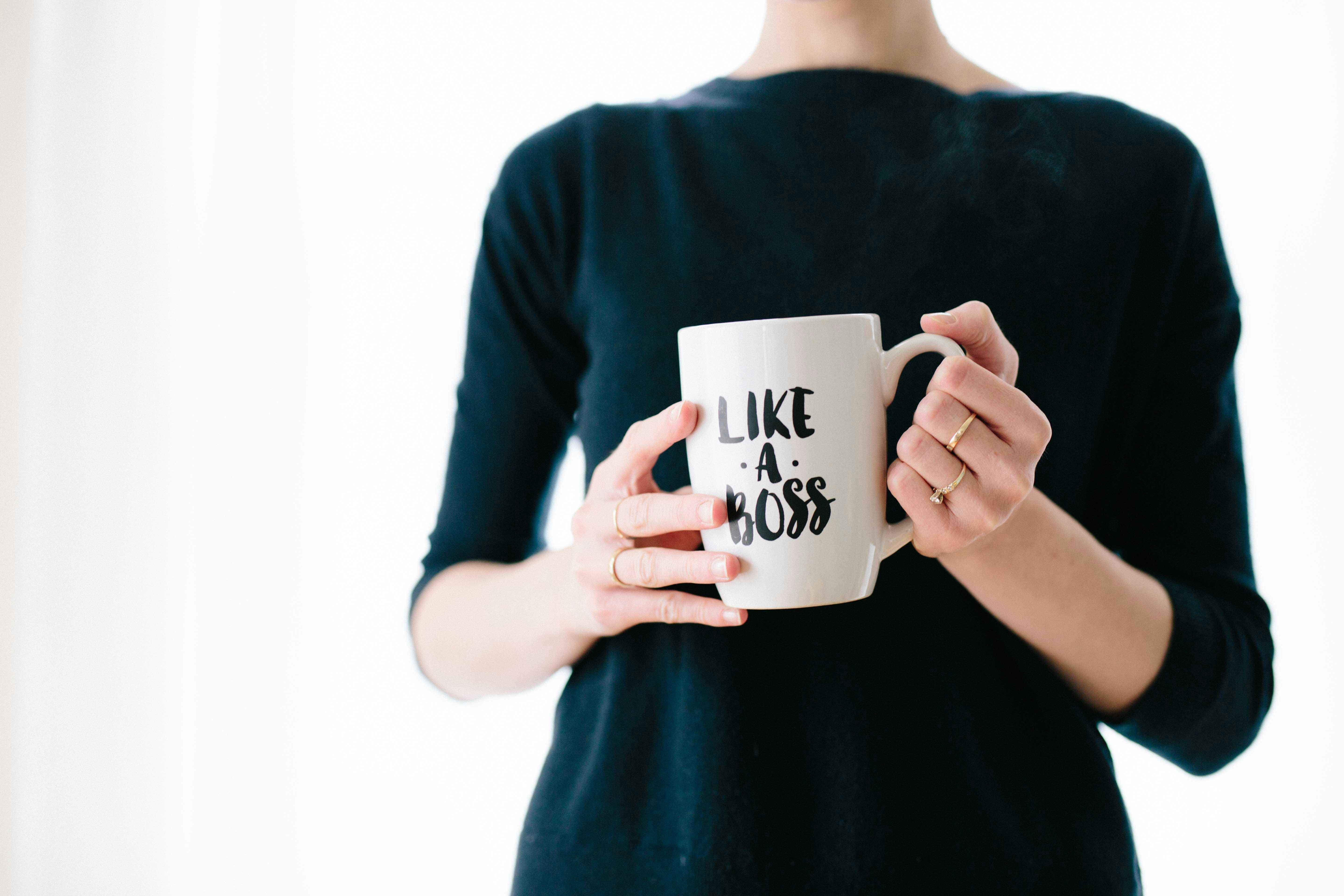 A women holds a mug with the words "Like a Boss" on the front of the mug. 