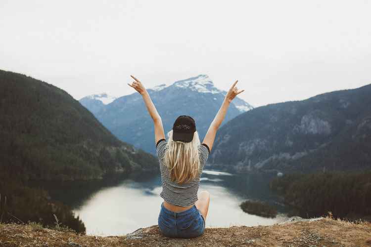 A woman celebrates the top of her hiking trail to symobolise stress relief.