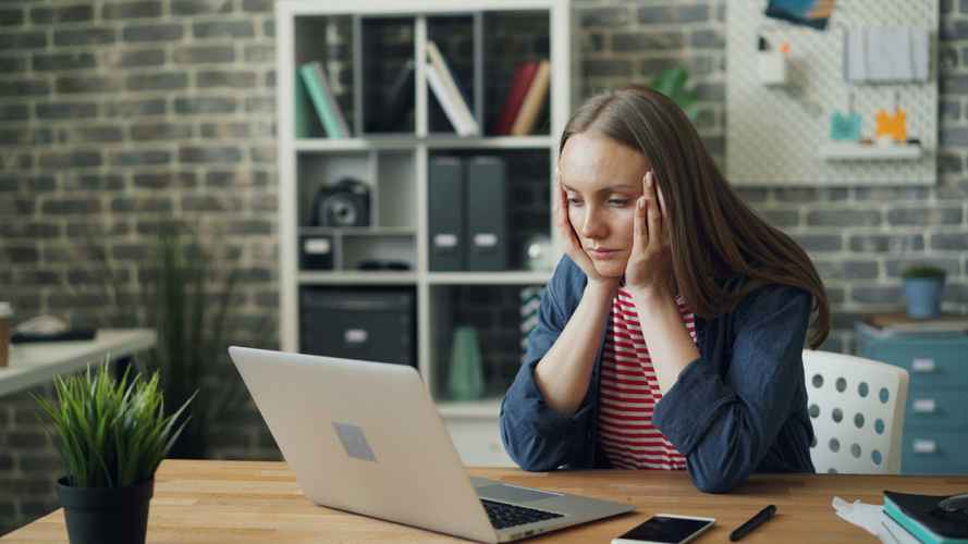 A woman at her work desk sits and smiles because she is feeling better.