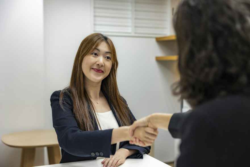 A woman smiles while shaking hands in an interview.