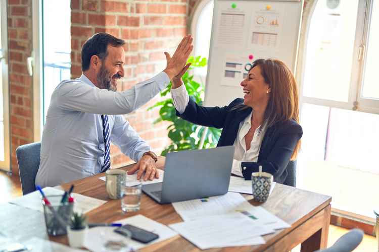 Colleagues high five happily at work.