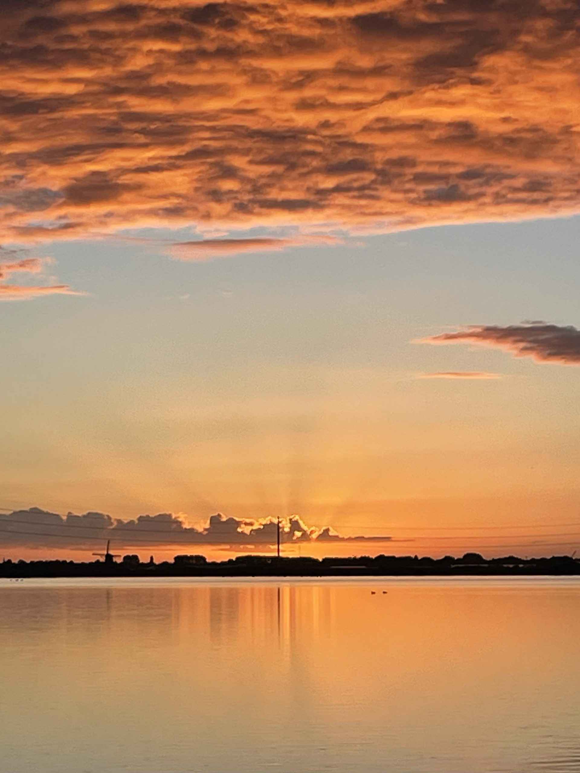 The sun peaking out behind orange clouds