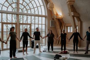 Deltagere står i rundkreds hånd i hånd til en tantra workshop i Siala
