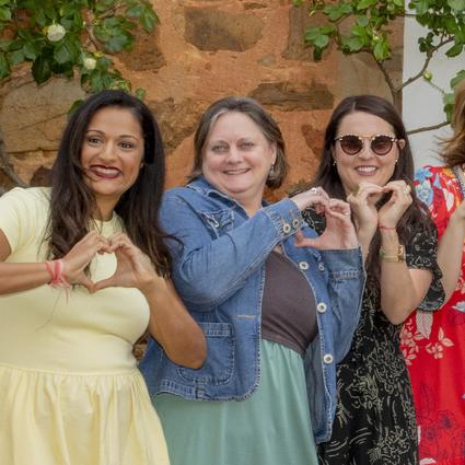 Three participants on our annual spain retreat make hearts with their hands smiling
