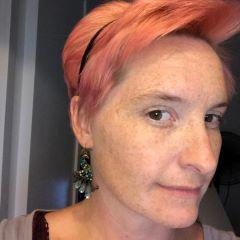 Julia O. with pink hair, portrait looking at the viewer thoughtfully