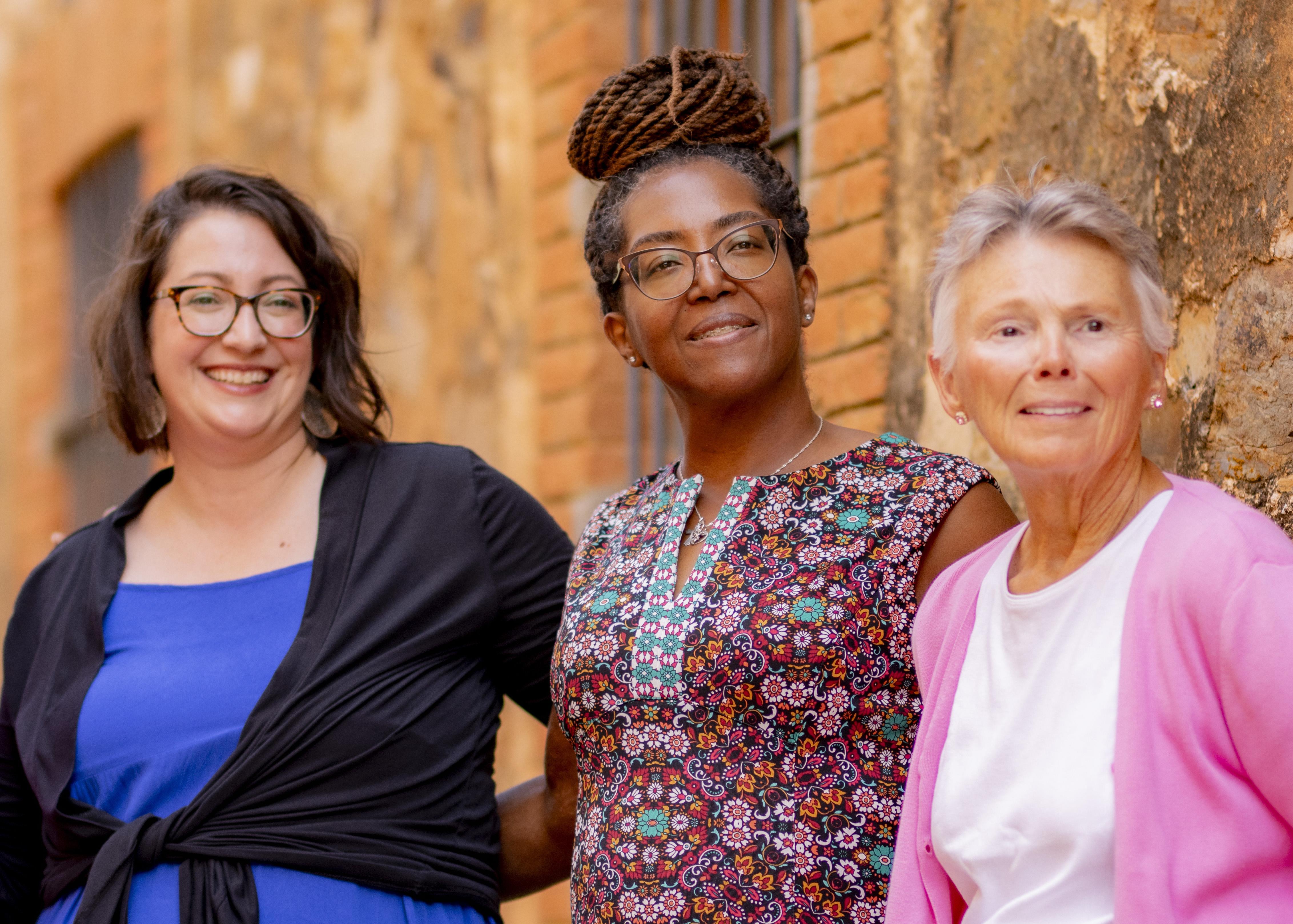Three women smiling together at Awaken’s Spain retreat, embodying empowerment coaching through community, presence, and authentic connection.