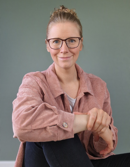 Lene Steinke, diætist og psykoterapeut bag Mind First, sidder med armen om knæet og smiler mildt – fokus på følelsesmæssig spisning og ro med mad