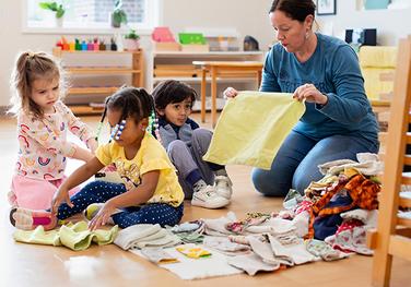 Montessori guide and children folding placemats in the classroom.