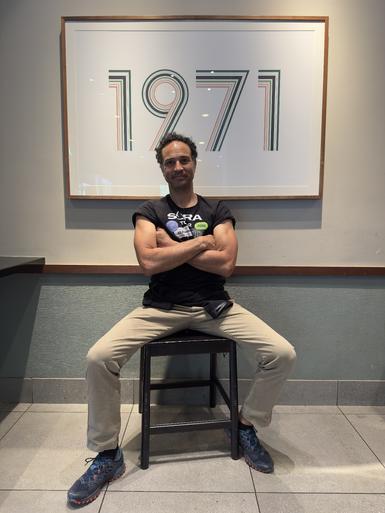 Photo of Adam sitting under a 1971 sign