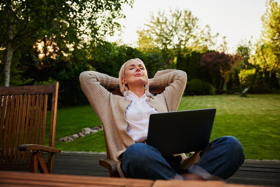 Kvinde sidder i haven med tablet og lukkede øjne