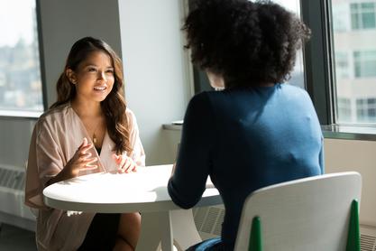 A business professional sits across from her executive leadership coach having a discussion