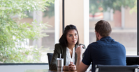 A leadership coaching session with a female executive and male executive leadership coach in a coffee shop