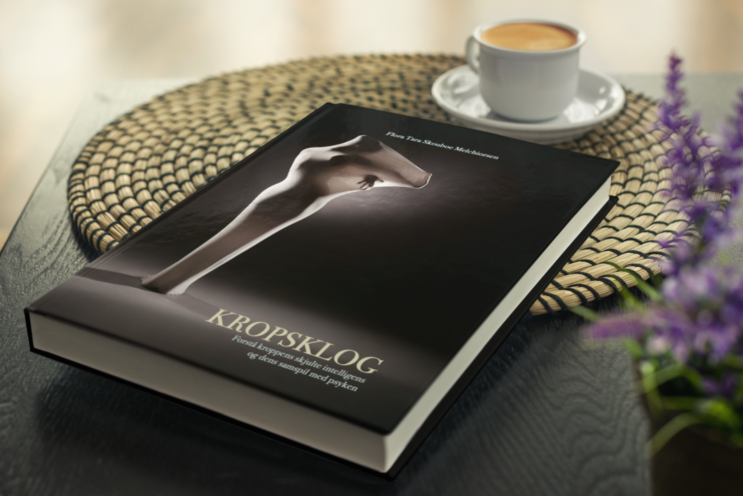 KROPSKLOG bog på bord med kaffe og lille blomst