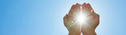 2 hænder hvor sollyser kniber igennem. Der er en blå himmel