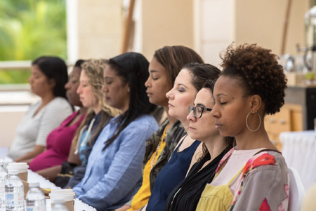 A group of individuals meditates at a table following Dr. Jill Wener's guidance during one of Jill's meditation courses.