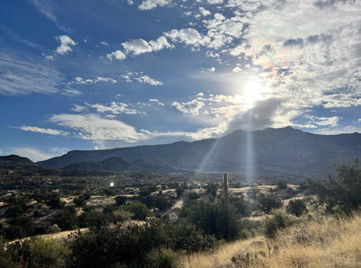 A view from the site of the Women in Healthcare Meditation Retreat at the Miraval Spa in Tucson, Arizona, with the sun shining over mountains on the horizon and a desert landscape in the foreground.