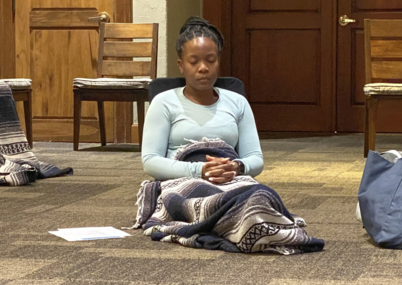 Learn to Meditate Comfortably and Easily / A retreat attendee sits in a relaxed posture meditating during a retreat session.