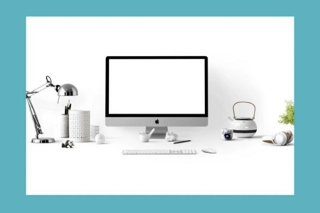 A computer screen sits on a desk with several desk accessories and a white background