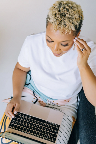 A woman is tapping along with an online tapping course, with her computer in her lap