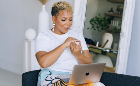 A woman with short blonde curly hair practices tapping using an online course on her computer