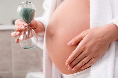 induction of labor pregnant woman holding an hourglass