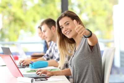 Happy-student-with-thumbs-up-in-a-classroom-820889590_3869x2579
