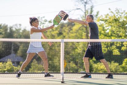 Two pickleball players at the night high fiving their pattles