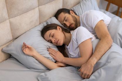 a man and a woman sleepping in a cozy bed snuggled together
