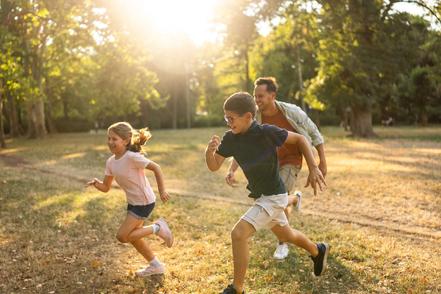 a boy, a girl, and their dad running in a field