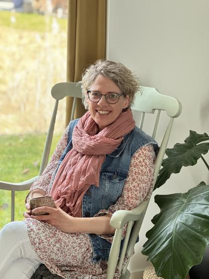 Karina sitting relaxed and smiling in a rocking chair