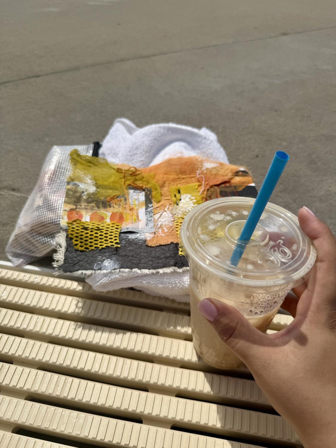 Iced coffee in hand with stitching project at pool&rsquo;s edge