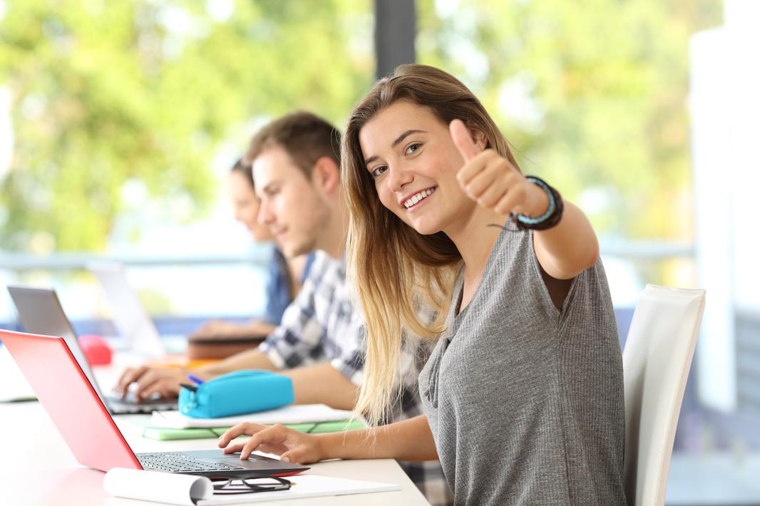 Happy-student-with-thumbs-up-in-a-classroom-820889590_3869x2579