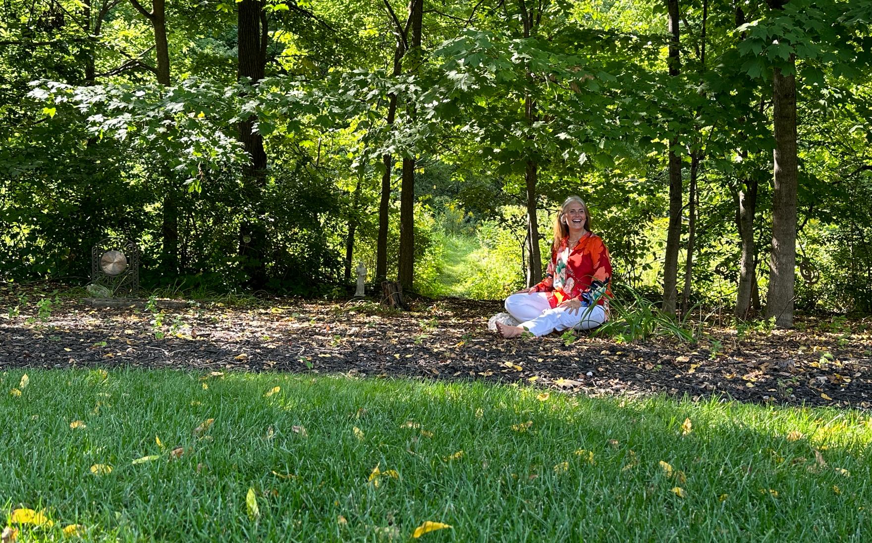 Header home page Pam sitting on rock with woods