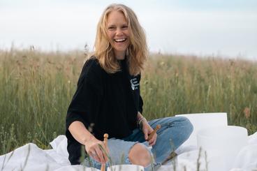 A photo of Randi with a welcoming smile while she plays the bowls in a freshly dew-filled field spreading joy to the nervous system of others