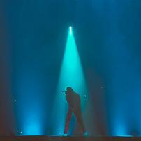 The silhouette of a singer on a stage with blue-green lighting
