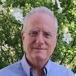 David B. Alexander, headshot in front of blossoming tree