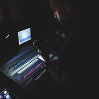 An audio engineer looking at a with sound board in front of him