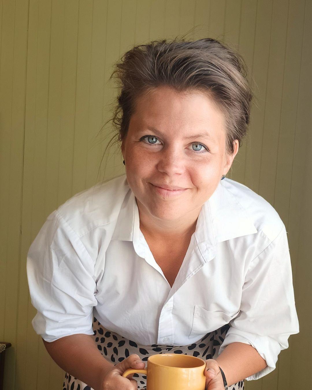 Ida Höglund i hvit skjorte med en gul kaffekopp