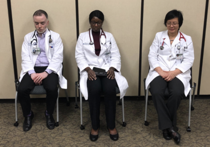 three doctors in white coats meditate while sitting in chairs