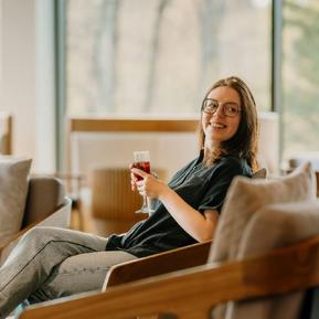 Smilende kvinde der sidder med et glas vin