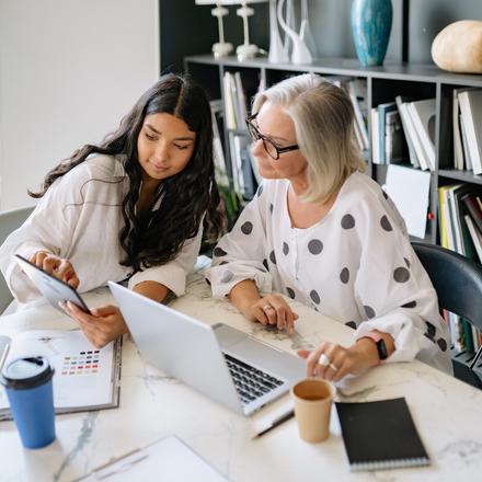 A younger woman helping an older woman with technology