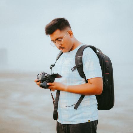 An asian man looking at a camera in a foggy area of a hike