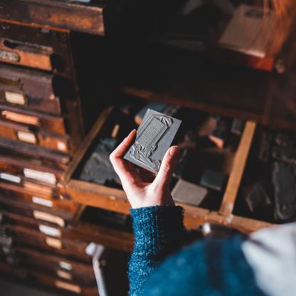 A hand pulling a stamp press out of a drawer