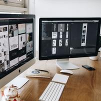 Two monitors showing website building screens