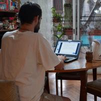 A man typing on a laptop on a round wooden table