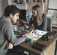 A man and a woman working on a project at a wooden table